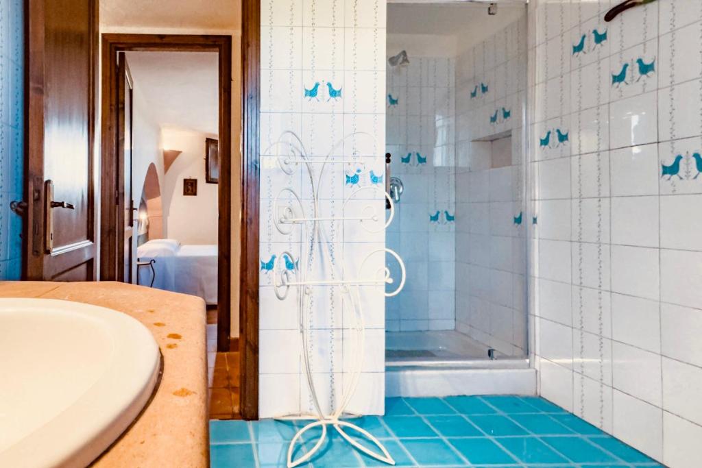 La salle de bains est pourvue d'une baignoire et d'une douche avec du carrelage bleu. dans l'établissement Porto Cervo Villas Swimming Pool - Sea View, à Porto Cervo