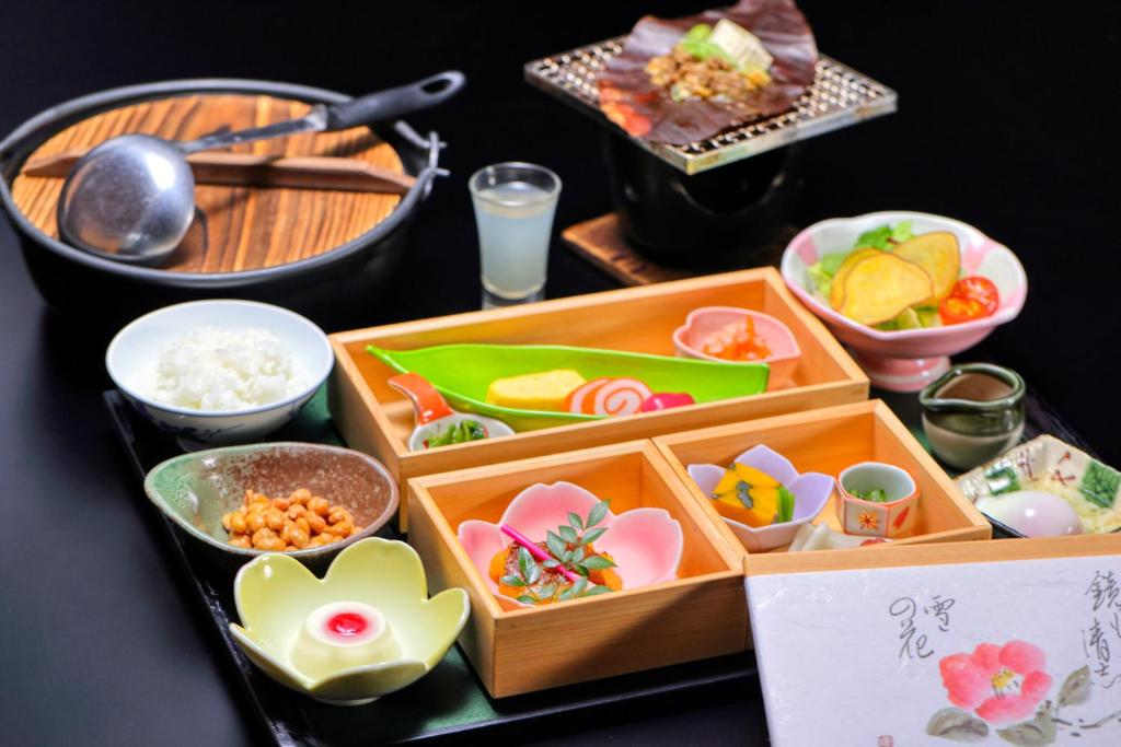 une table avec une boîte de nourriture et d'autres plats dans l'établissement Miyama Ouan Kyoritsu Resort, à Takayama