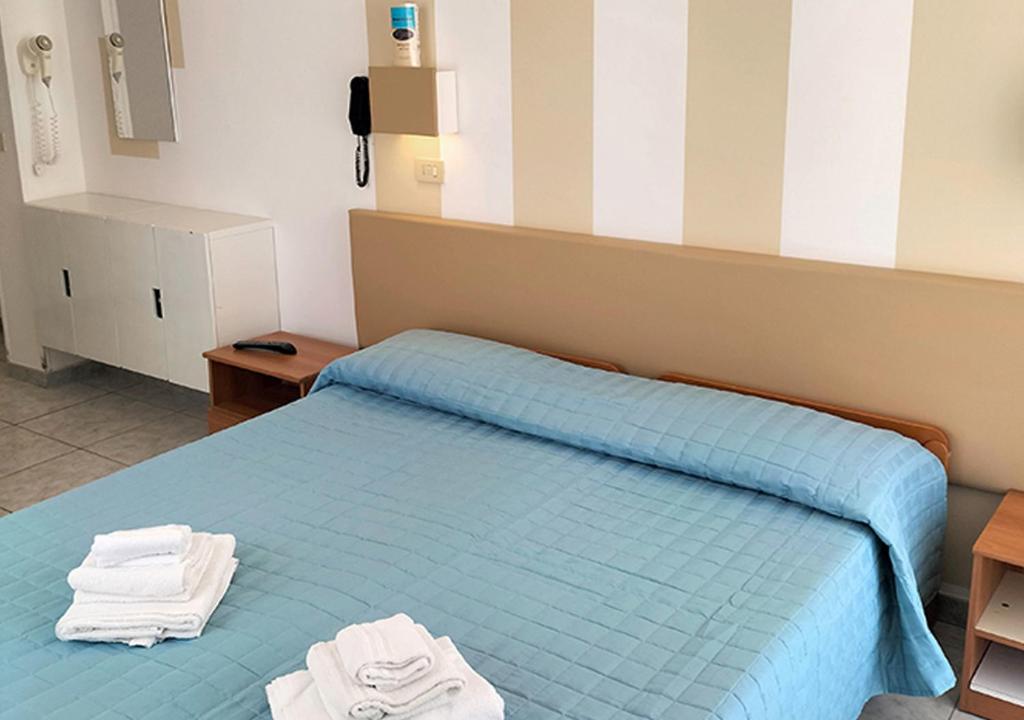 une chambre avec un lit bleu avec deux serviettes dessus dans l'établissement Hotel Cà Vanni, à Rimini