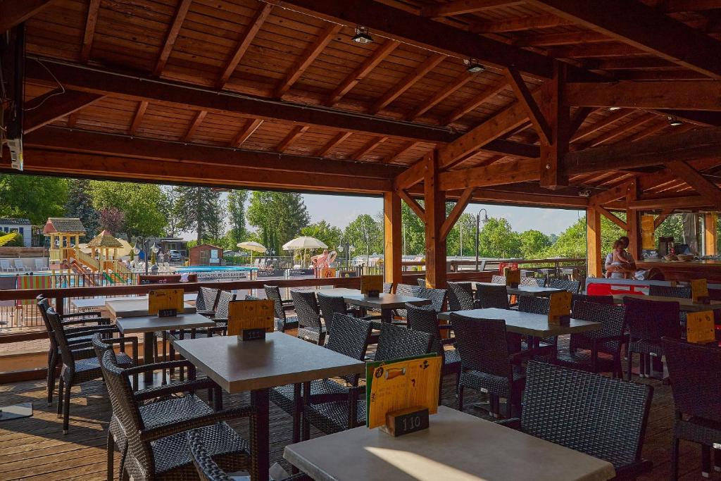 un restaurant en plein air avec des tables et des chaises ainsi qu'une aire de jeux dans l'établissement Camping Le Chêne Gris, à Pommeuse