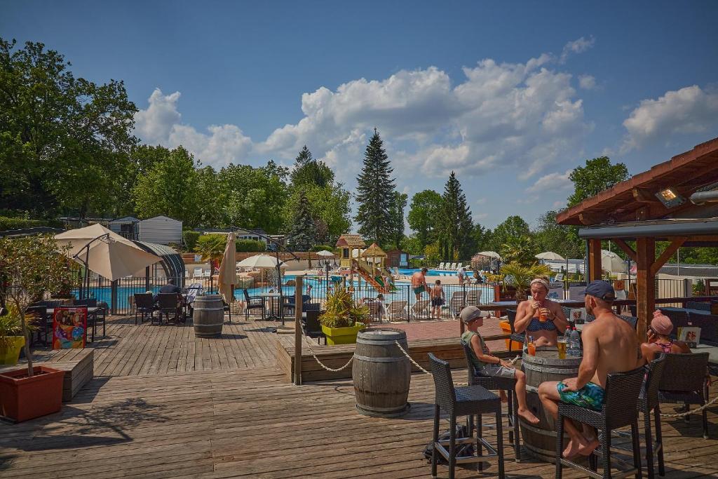 un groupe de personnes assises sur des chaises près d'une piscine dans l'établissement Camping Le Chêne Gris, à Pommeuse