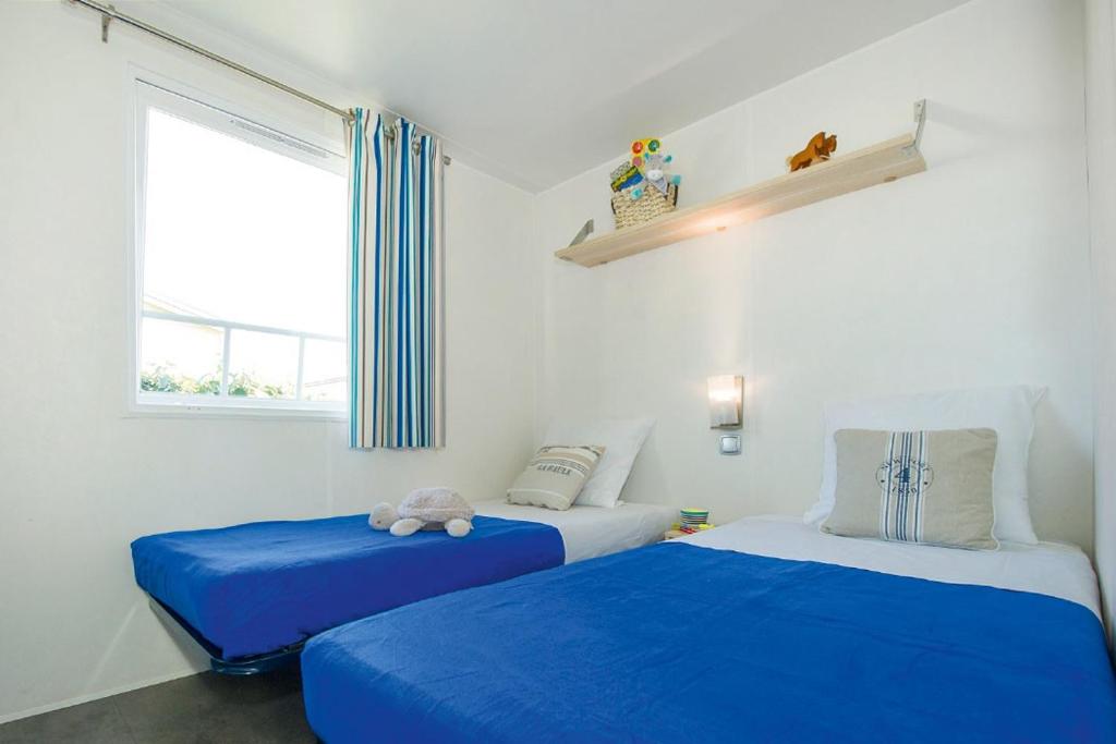 - une chambre avec 2 lits avec des draps bleus et une fenêtre dans l'établissement Camping Le Chêne Gris, à Pommeuse