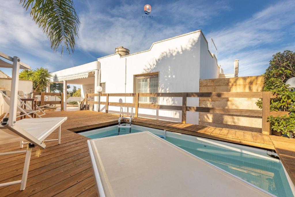 une maison avec une piscine sur une terrasse en bois dans l'établissement Villa La Palma By Vivimy, à Taviano