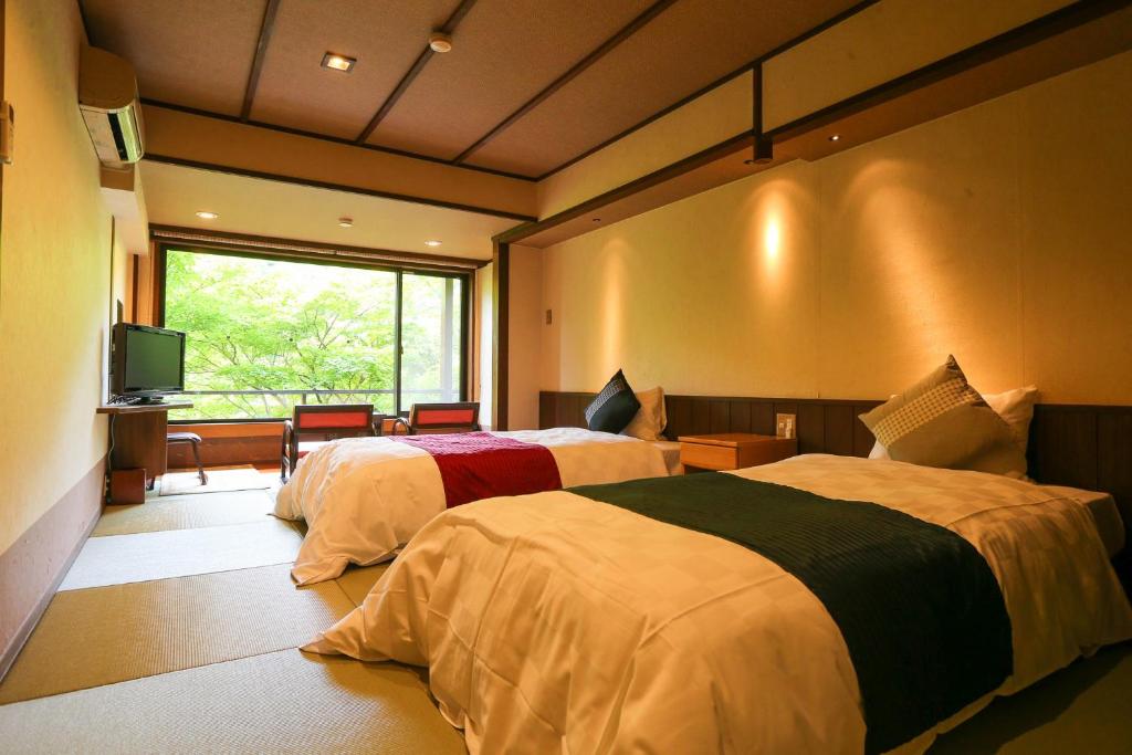 une chambre d'hôtel avec deux lits et une télévision dans l'établissement Momijiya Honkan Takaosansou, à Kyoto