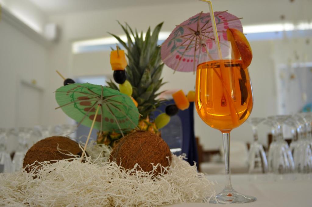 une table avec un verre de jus d'orange et des sandicans avec des parapluies dans l'établissement Hotel Souvenir, à Caorle