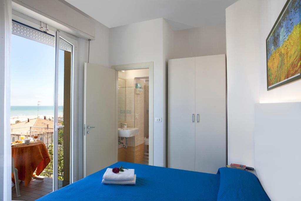 - une chambre avec un lit bleu et une vue sur l'océan dans l'établissement Hotel Leoni, à Rimini