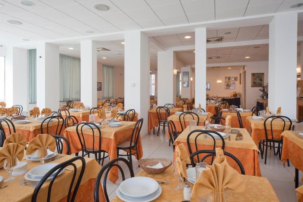 - une salle à manger avec des tables et des chaises dans l'établissement Hotel Leoni, à Rimini