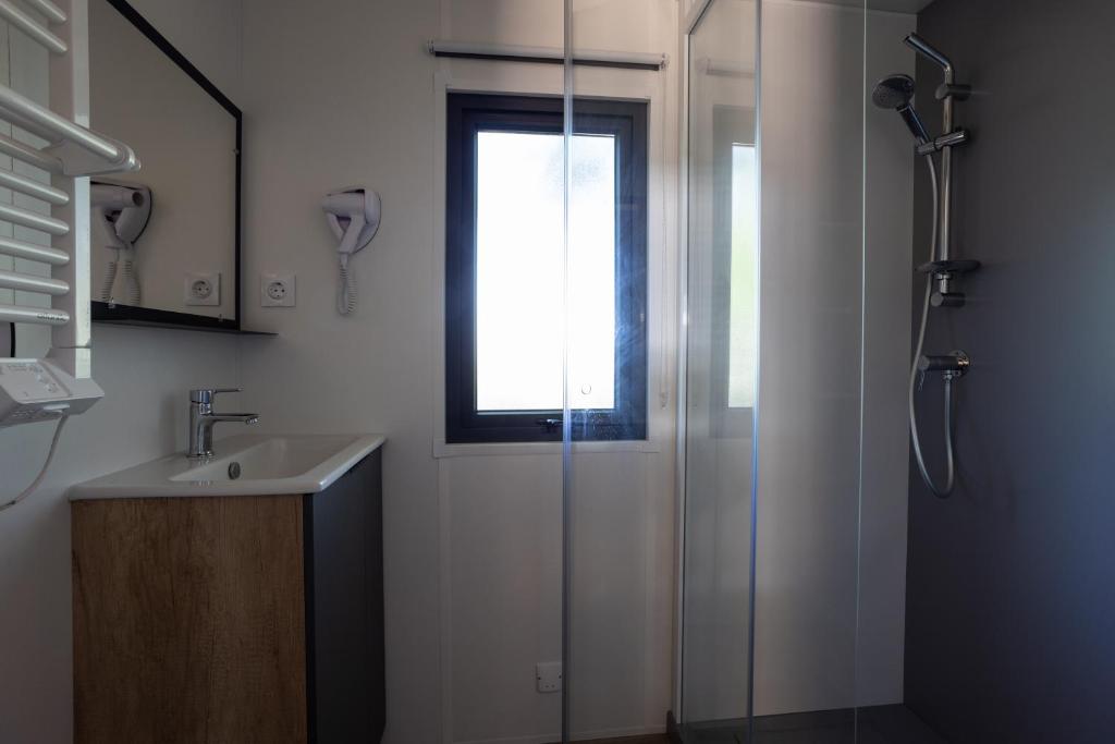 une salle de bain avec une douche et un lavabo et une fenêtre dans l'établissement Camping Sites et Paysages Les Prés Hauts, à Sisteron
