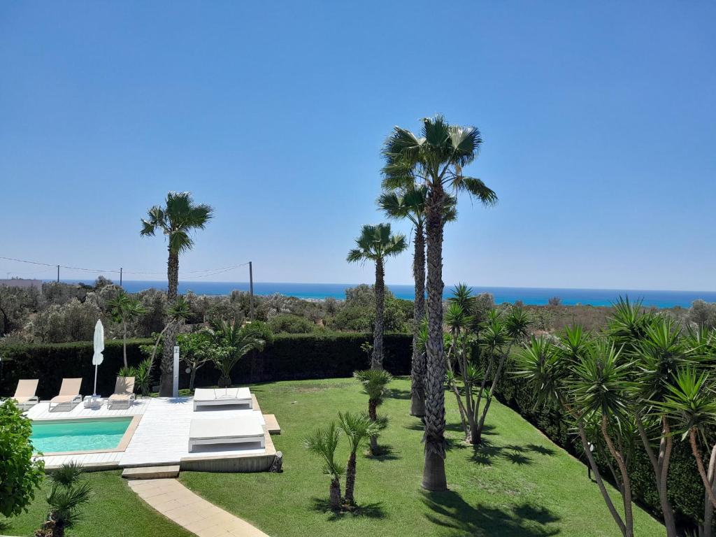 un jardin avec des palmiers et une piscine dans l'établissement Villa Gina by Perle di Puglia, à Torre San Giovanni
