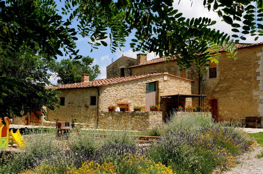 une vieille maison en pierre avec un jardin devant dans l'établissement Sant'Ippolito, à Asciano