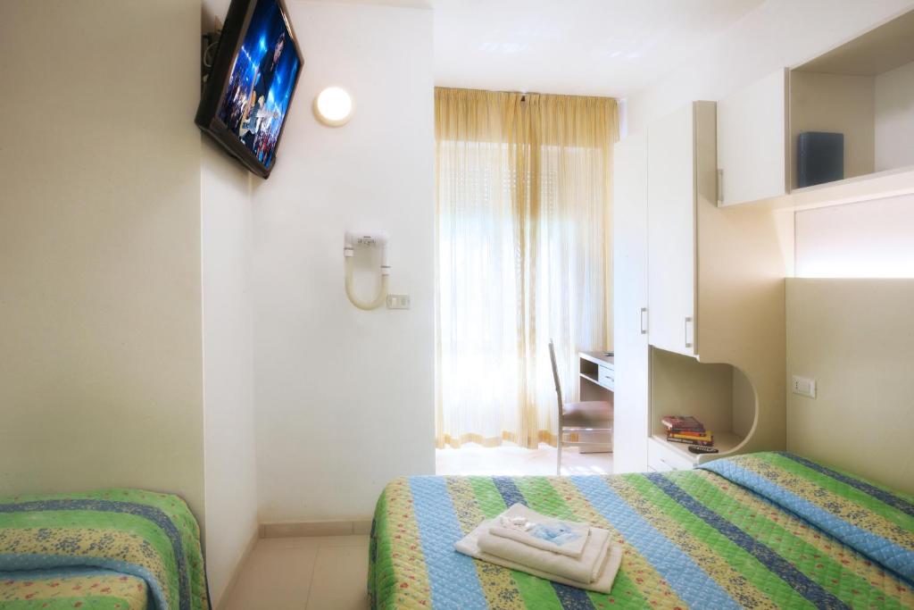 une chambre d'hôtel avec deux lits et une télévision dans l'établissement Hotel Leoni, à Rimini