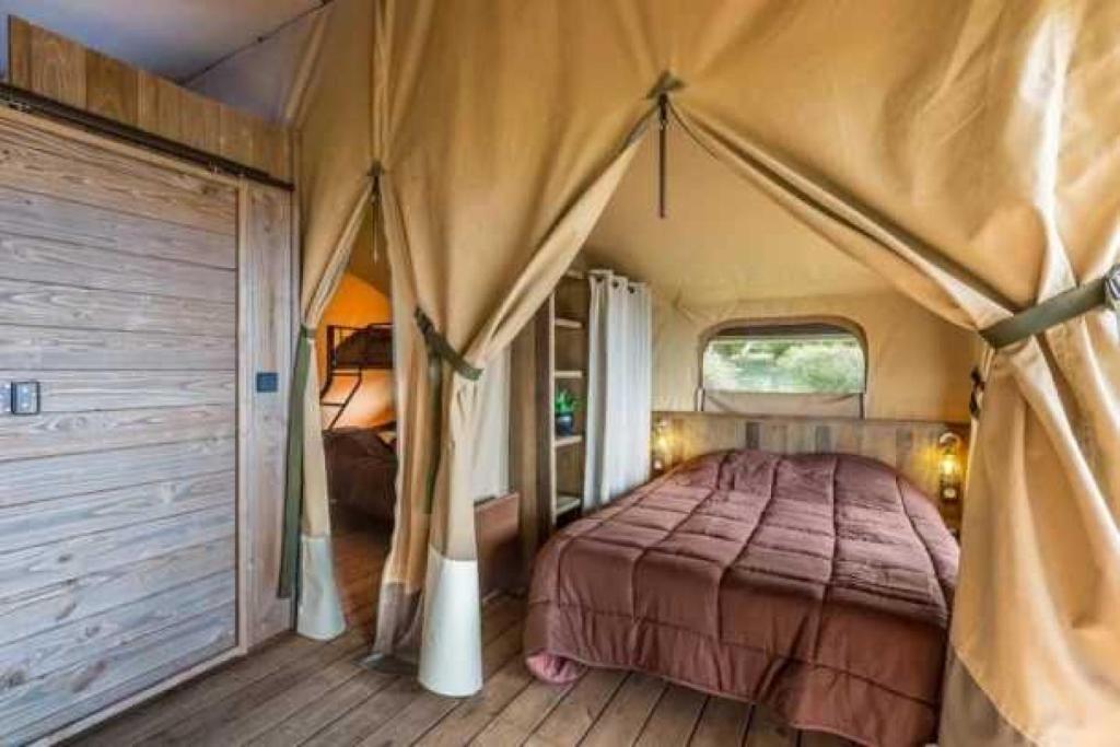 une chambre avec un lit dans une tente dans l'établissement Camping 3 étoiles - Piscine - eeebcb, à Roquebrune-sur Argens