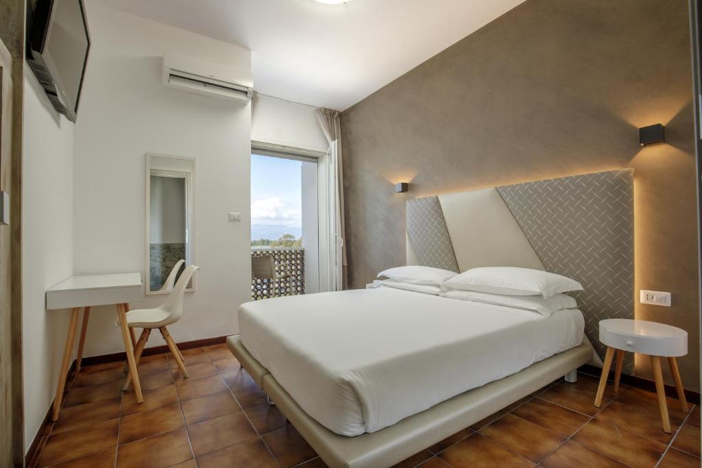 une chambre avec un grand lit blanc et un bureau dans l'établissement Hotel Tirreno, à Latina
