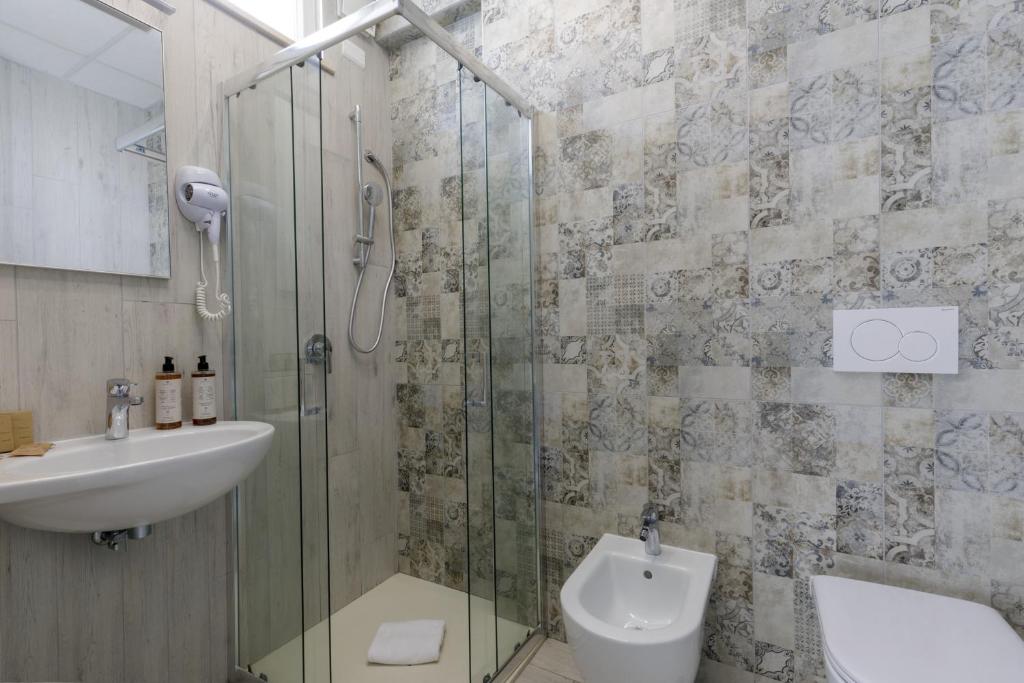 une salle de bain avec douche, lavabo et toilettes dans l'établissement Hotel Tirreno, à Latina