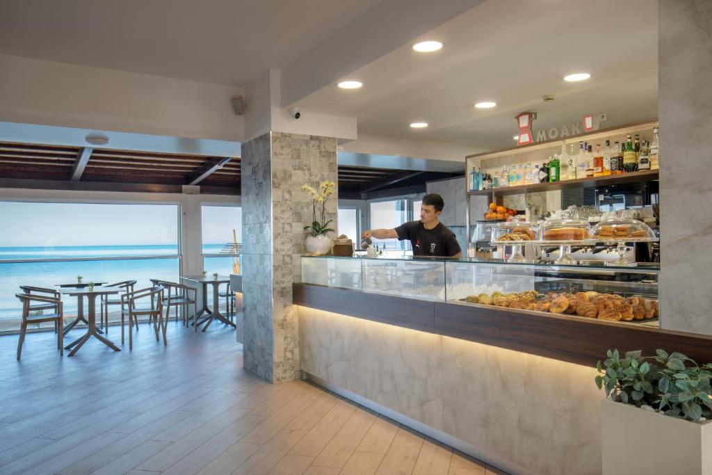 un homme se tient derrière un comptoir dans un restaurant dans l'établissement Hotel Tirreno, à Latina