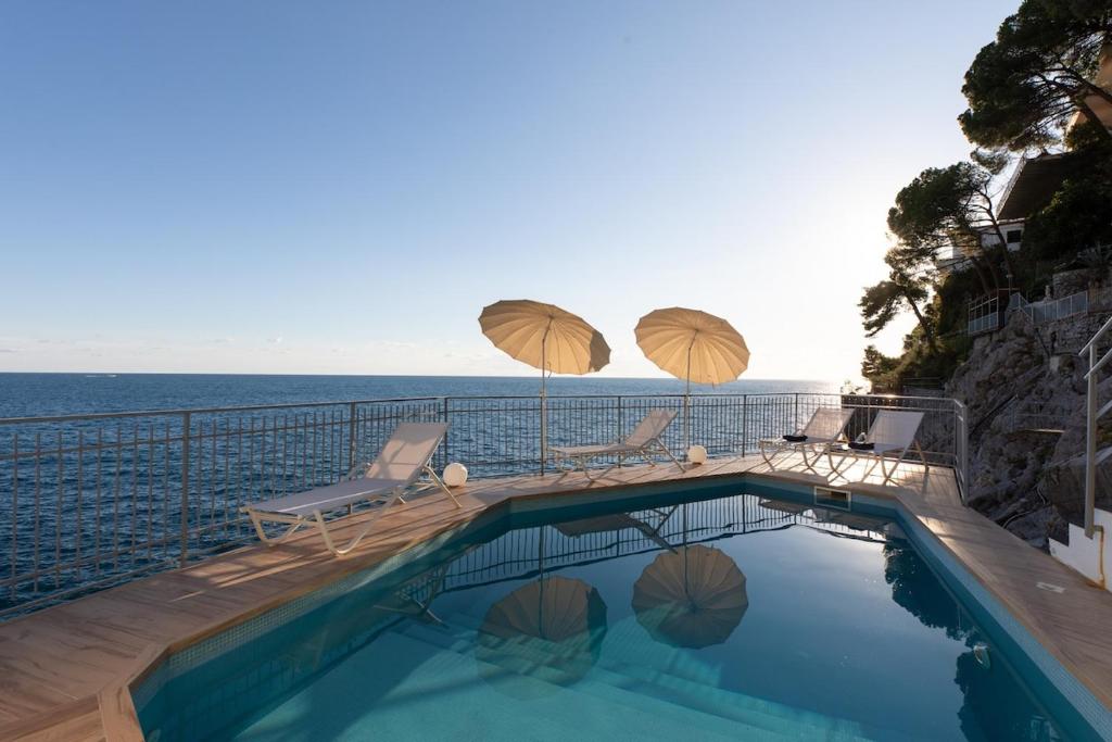 - une piscine avec 2 parasols et 2 chaises longues ainsi qu'une piscine dans l'établissement Villa Elizabeth, à Conca dei Marini