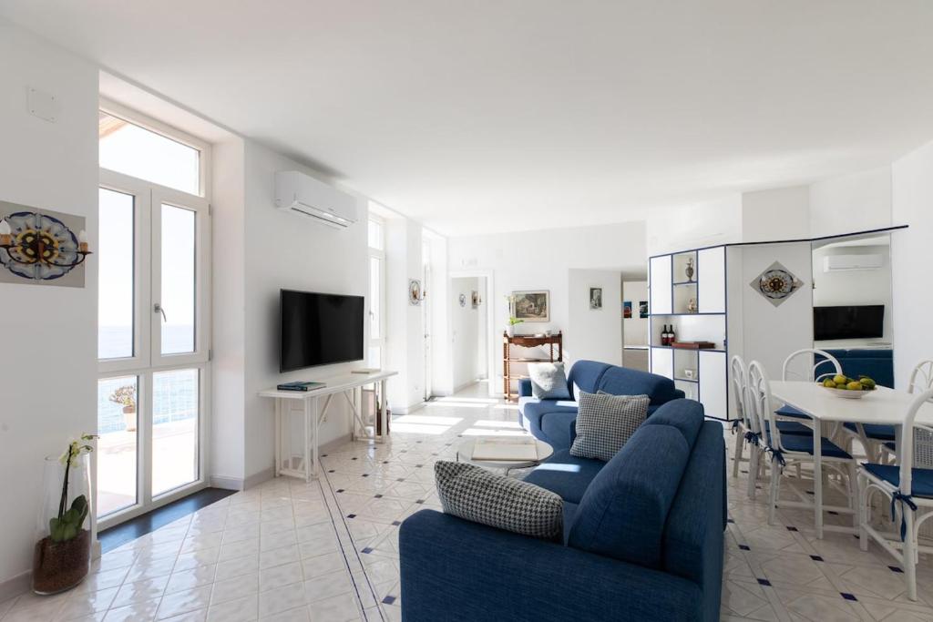 un salon avec deux chaises bleues et une télévision dans l'établissement Villa Elizabeth, à Conca dei Marini