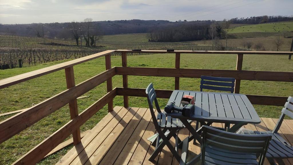 une table et des chaises sur une terrasse avec vue sur un champ dans l'établissement Chaleureuse yourte a la campagne, à Mourens