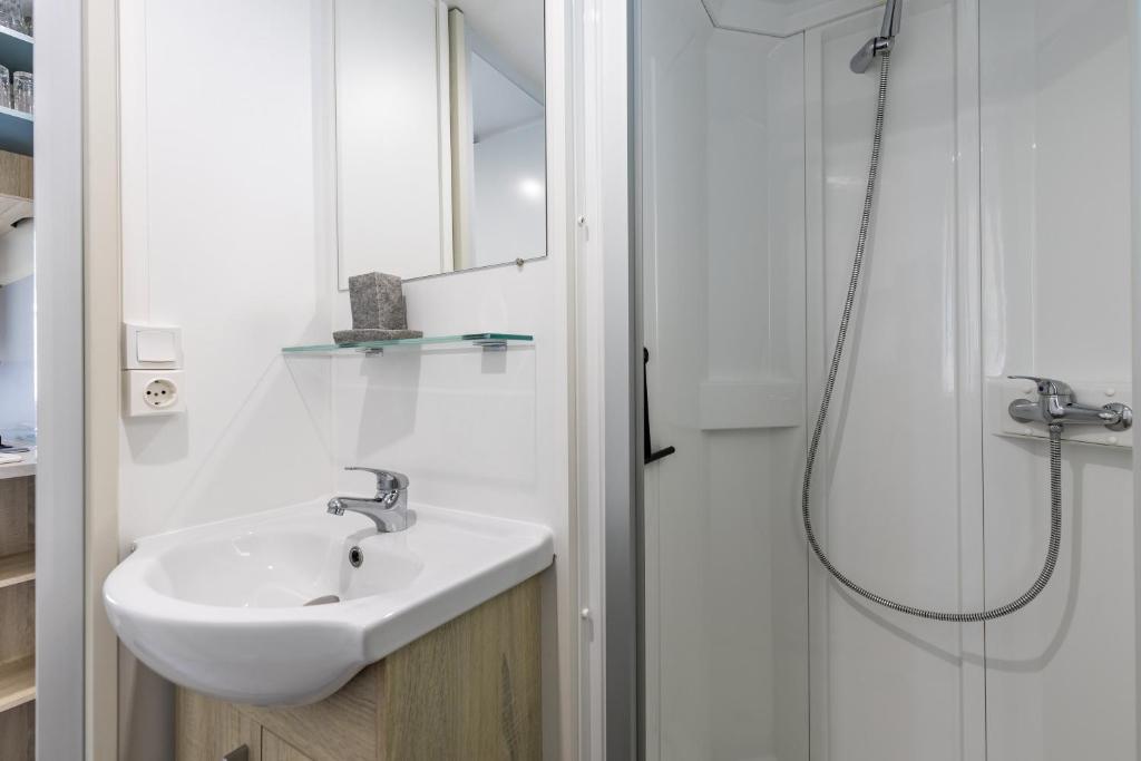 une salle de bain blanche avec un lavabo et une douche dans l'établissement Mobilhome 6-8 personnes Cap Ferret, à Lège-Cap-Ferret