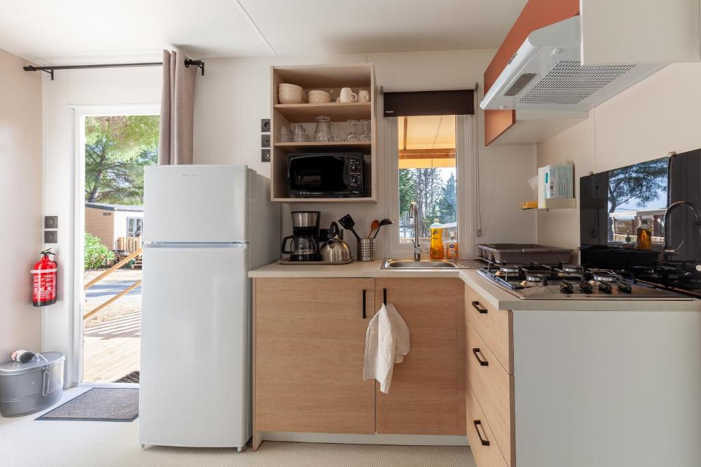 une cuisine avec un réfrigérateur blanc et un évier dans l'établissement Mobil home tout équipé, à Carry-le-Rouet