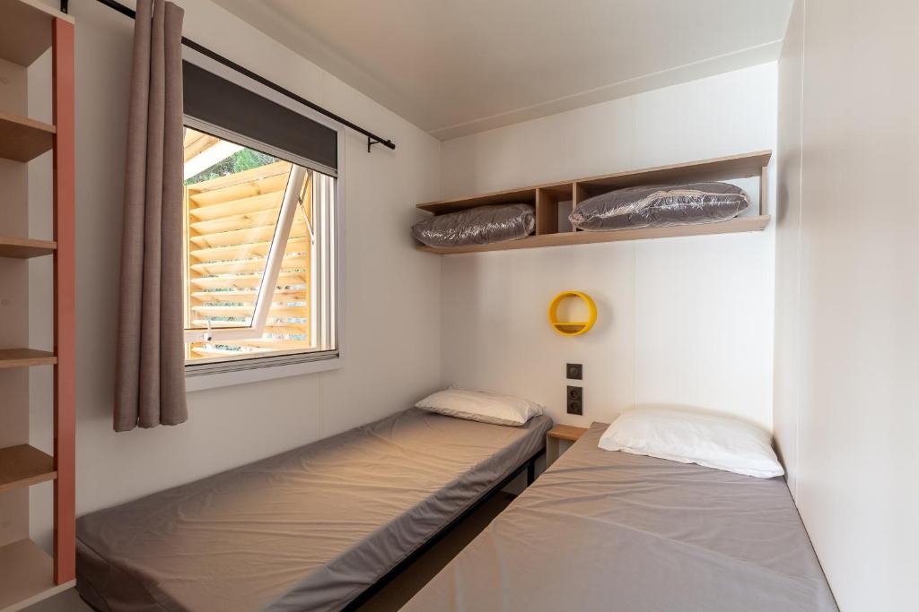 deux lits dans une chambre avec une fenêtre dans l'établissement Mobil home tout équipé, à Carry-le-Rouet 34 autres photos