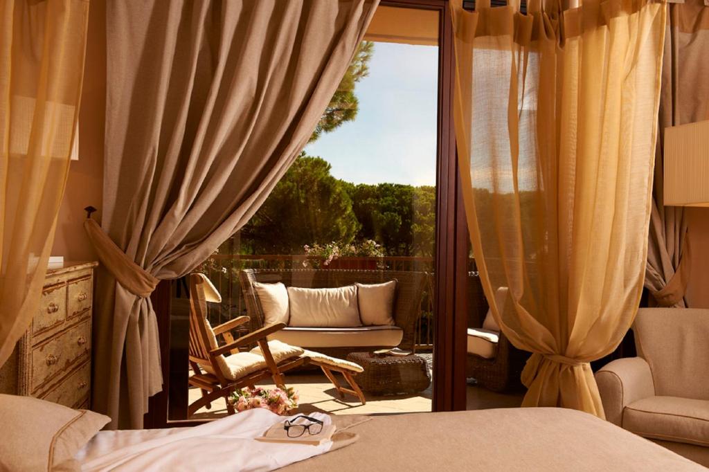 - une chambre avec un lit et un balcon avec une chaise dans l'établissement Roccamare Resort - Casa di Ponente, à Castiglione della Pescaia