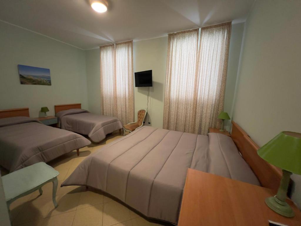 une chambre d'hôtel avec deux lits et une télévision dans l'établissement Hotel Geranio Rosso, à Stintino
