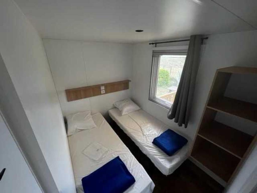 une petite chambre avec deux lits et une fenêtre dans l'établissement Camping 2 étoiles - Piscine - ccb0fdi, à Villeneuve-lès-Maguelone