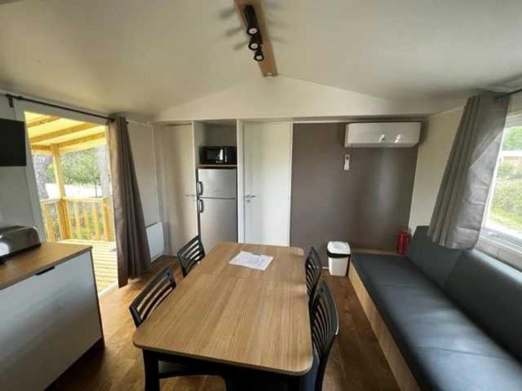 une salle à manger avec une table, des chaises et un canapé dans l'établissement Camping 2 étoiles - Piscine - ccb0fdi, à Villeneuve-lès-Maguelone