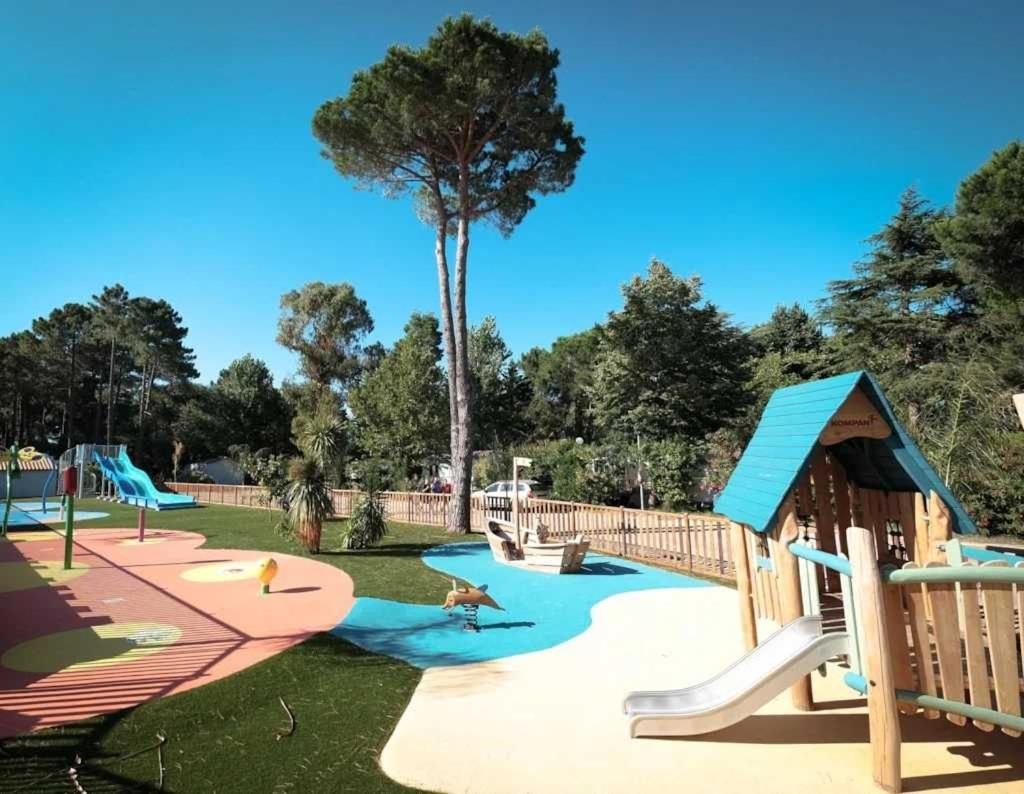 une aire de jeux avec un toboggan, des toboggans et un arbre dans l'établissement Camping 4 étoiles - Piscine - ccb0e00, à Argelès-sur-Mer