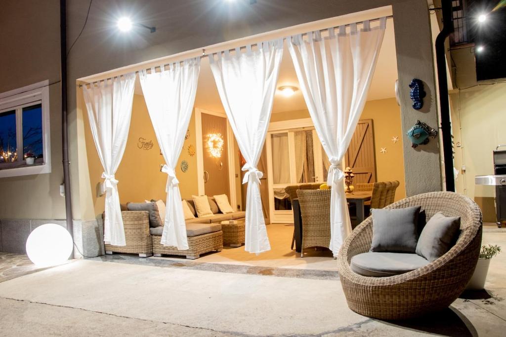 - un salon avec des rideaux blancs et des chaises en osier dans l'établissement Country Relais Villa Margherita, à Pralormo