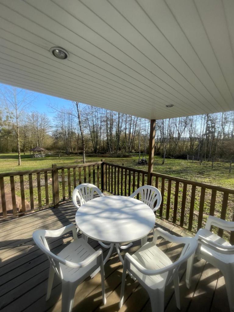 une table et des chaises blanches sur une terrasse en bois dans l'établissement logement au coeur de la nature, à Le Grand-Lucé