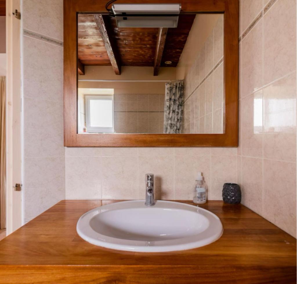 un lavabo blanc dans une salle de bain avec un miroir dans l'établissement Gîte de Lafargue - maison en pierre lumineuse, à Cazes-Mondenard