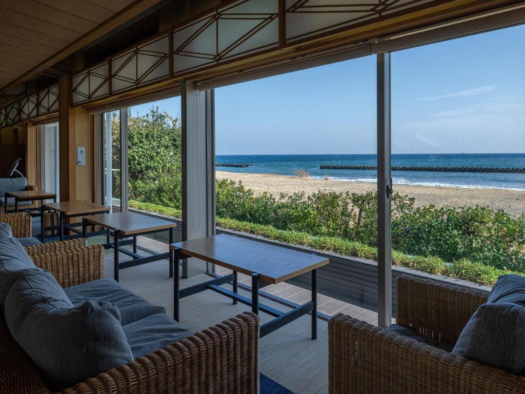 une chambre avec des tables et des chaises et une vue sur la plage dans l'établissement Kaiyutei, à Kawazu