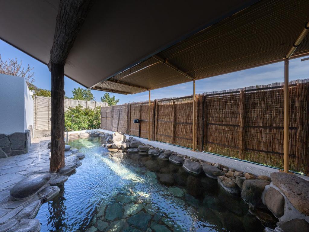 une piscine d'eau avec des rochers dans une maison dans l'établissement Kaiyutei, à Kawazu