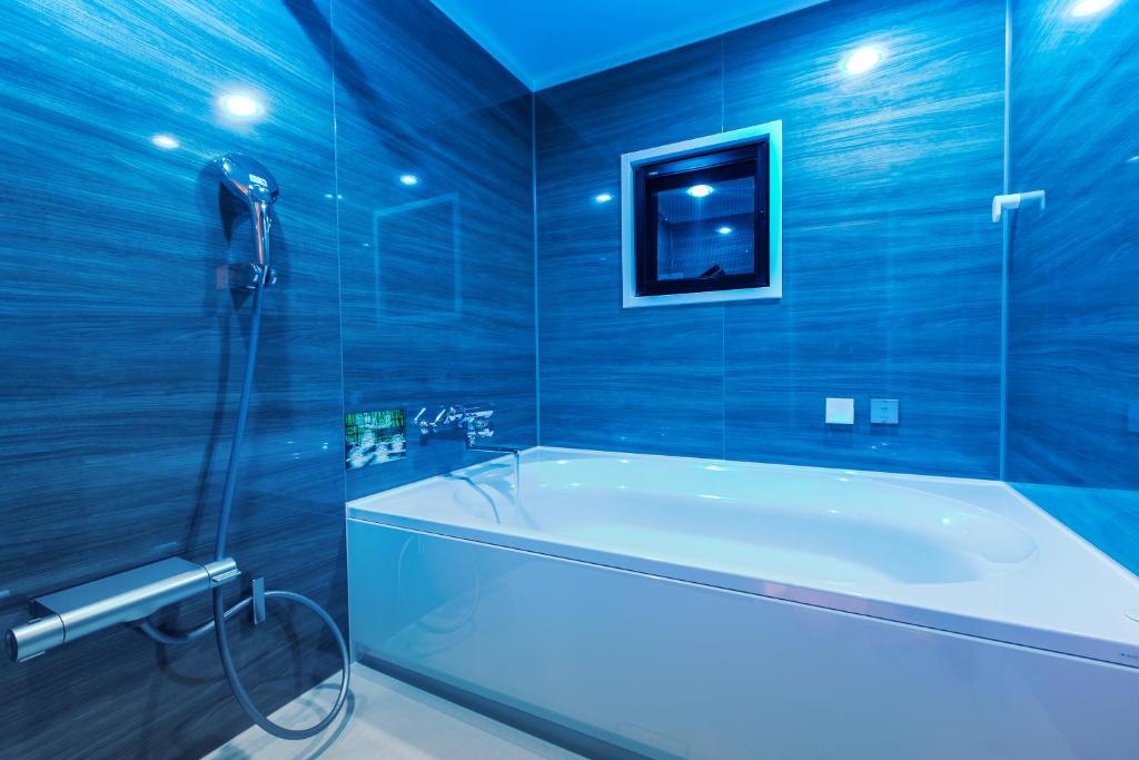 La salle de bains bleue est pourvue d'une baignoire et d'une douche. dans l'établissement ホテルジップスタイル, à Sendohira