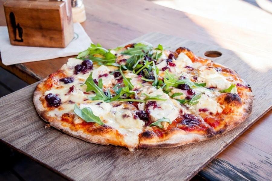 une pizza assise sur une planche de découpe en bois dans l'établissement Camping maeva Escapades Country Park - Touquin, à Touquin