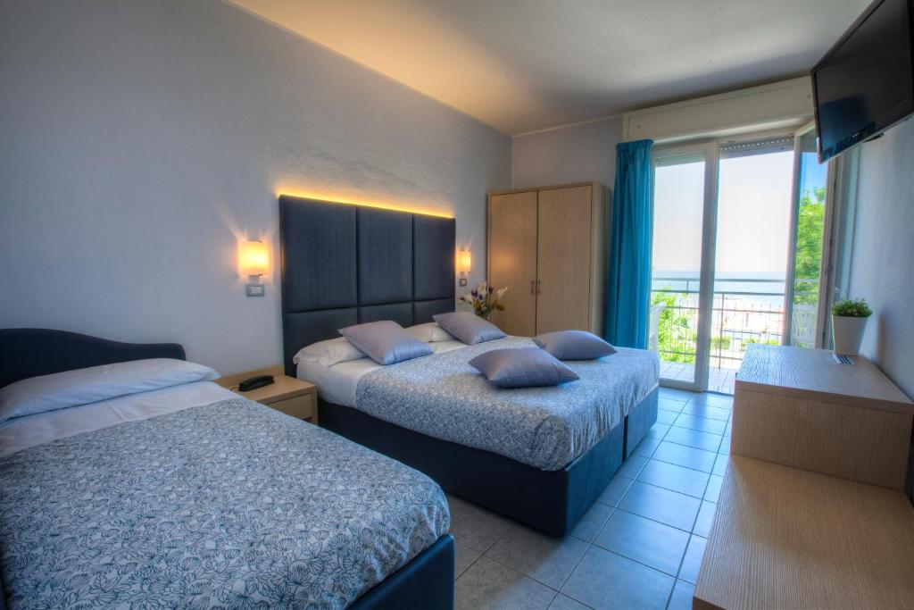 une chambre d'hôtel avec deux lits et un balcon dans l'établissement Baby Family Hotel Alda Amelia, à Cattolica 32 autres photos