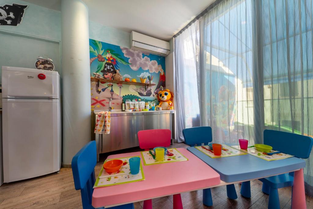 une chambre d'enfant avec une table, des chaises et un réfrigérateur dans l'établissement Baby Family Hotel Alda Amelia, à Cattolica