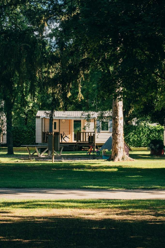 une petite cabane dans un parc avec un arbre dans l'établissement Camping intercommunal de Beaurepaire, à Beaurepaire