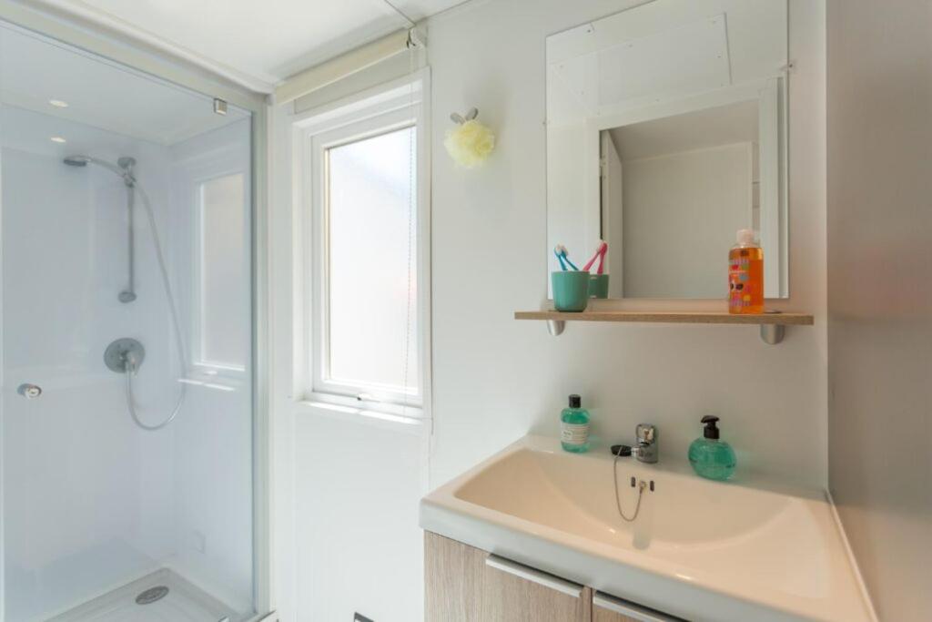 une salle de bain avec un lavabo, un miroir et une douche dans l'établissement Camping La Pointe Saint-Gildas - Maeva, à Préfailles