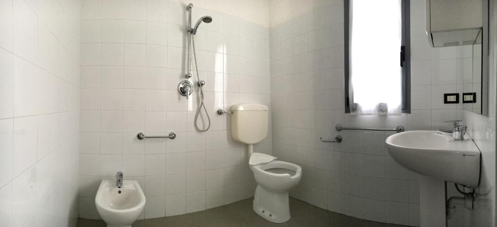 une salle de bain blanche avec toilettes et lavabo dans l'établissement Appartamenti Villaggio Internazionale, à Albenga