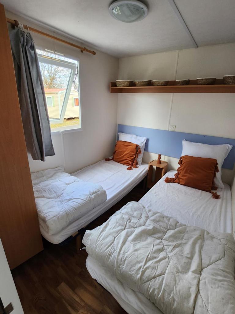 une chambre avec deux lits et une fenêtre dans l'établissement Mobilhome les pieds dans l eau avec piscine, à Saint-Gérons