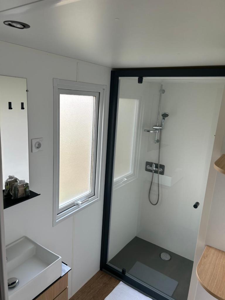 une salle de bain avec une douche, un lavabo et un miroir dans l'établissement les sables du midi valras plage, à Sérignan