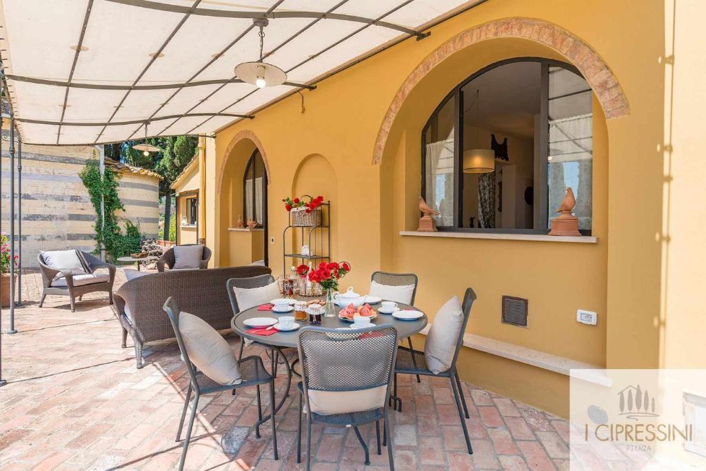 un patio avec une table et des chaises sur un patio dans l'établissement Villa Le Tortore privata lusso piscina relax Siena, à Sienne