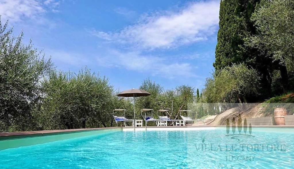 une piscine avec des chaises et un parasol dans l'établissement Villa Le Tortore privata lusso piscina relax Siena, à Sienne