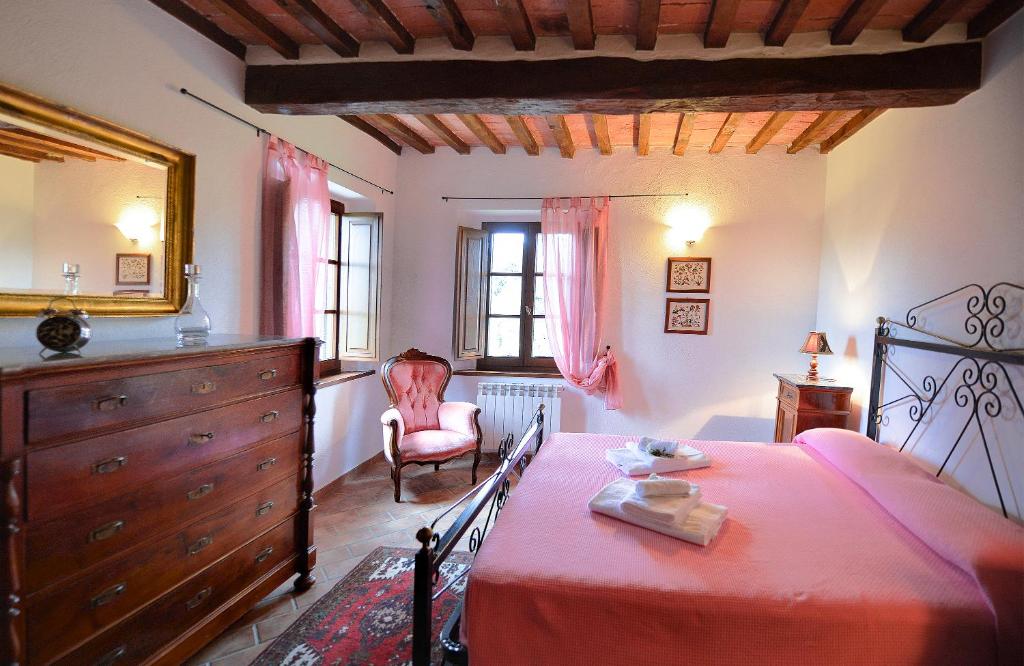 - une chambre avec un lit, une commode et une chaise dans l'établissement Podere Suvignano, à Murlo