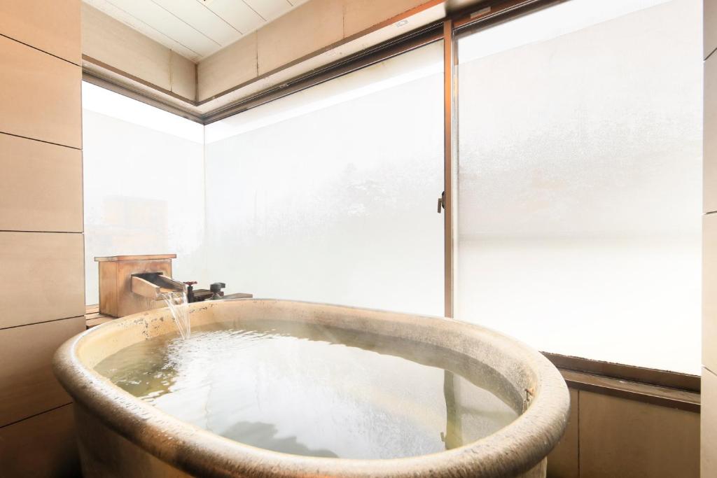 une baignoire dans une salle de bain avec une fenêtre dans l'établissement Naruko Fuga, à Osaki