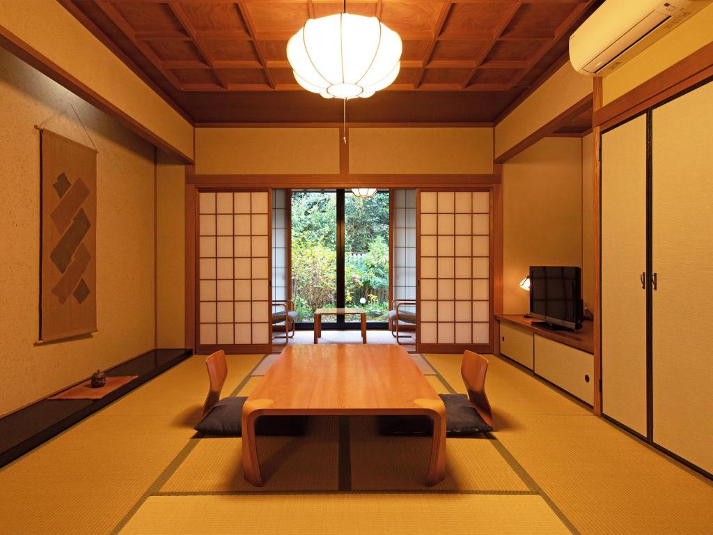 une pièce avec une table, des chaises et une télévision dans l'établissement Yufuin Onsen Ryokan Hananomai, à Yufu