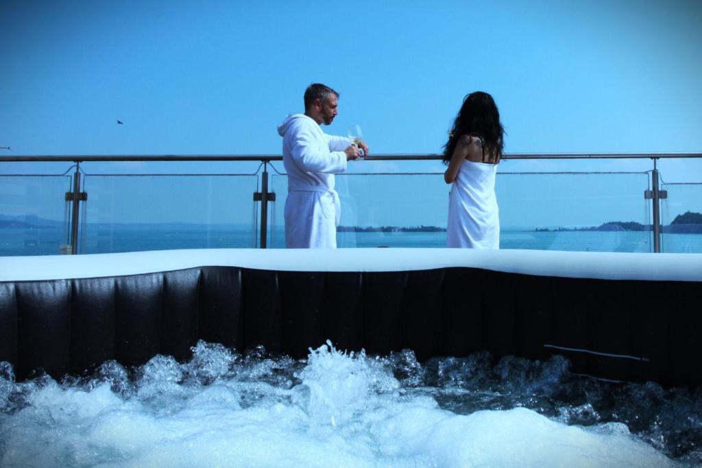 un homme et une femme debout au bord d'une baignoire dans l'établissement Happy Hotel Atelier Gardone Riviera Centro & Spa, à Gardone Riviera